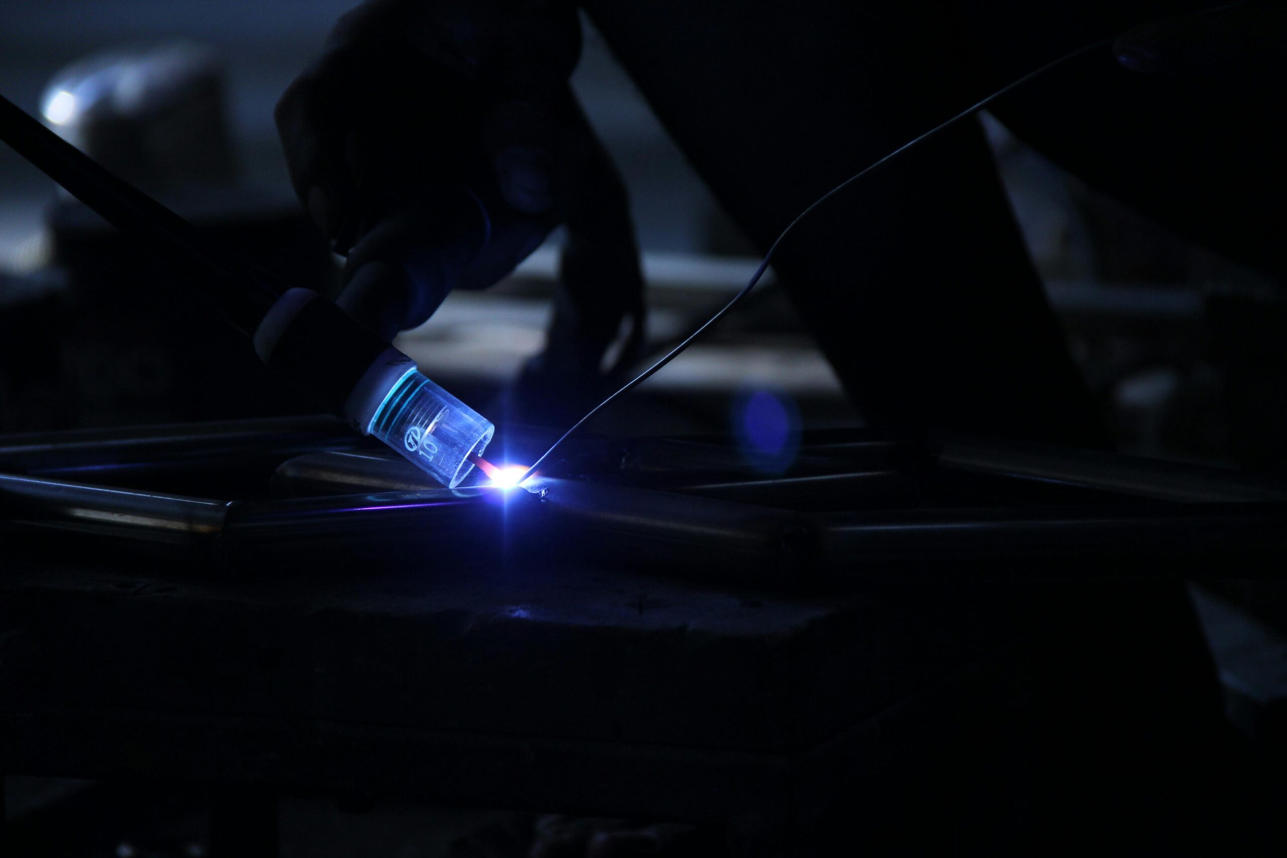 Intense close-up of a welding process in a dark industrial setting, showcasing sparks and precision.